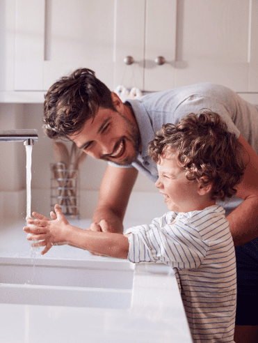 Father teaching child handwashing at sink