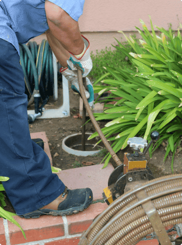 Plumber operating drain snake auger cleaning equipment